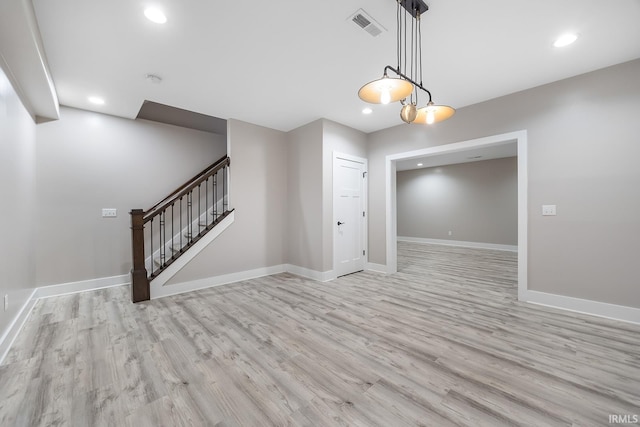 spare room with stairway, wood finished floors, visible vents, and baseboards