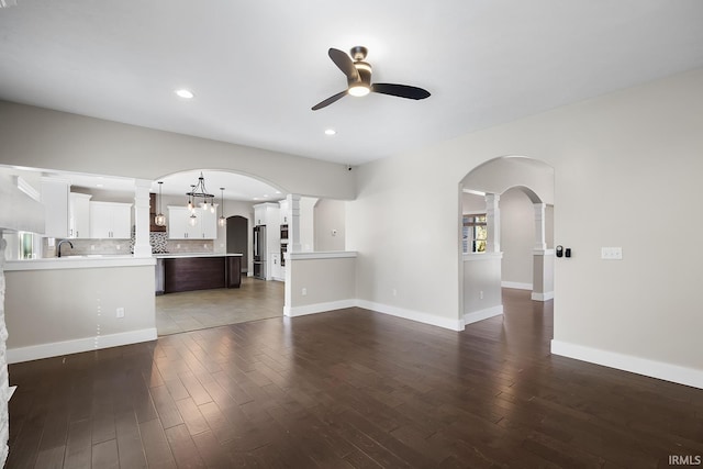 unfurnished living room featuring dark wood-style floors, ceiling fan, arched walkways, and recessed lighting