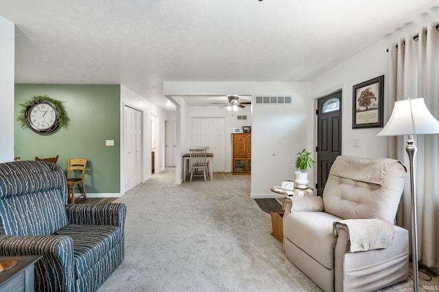 carpeted living room with baseboards, visible vents, and a ceiling fan