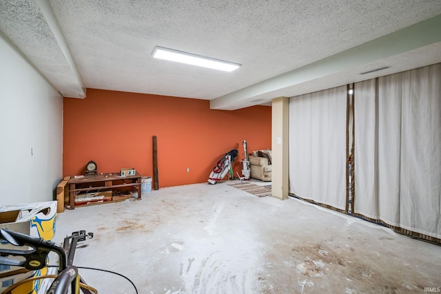 finished basement with a textured ceiling and visible vents