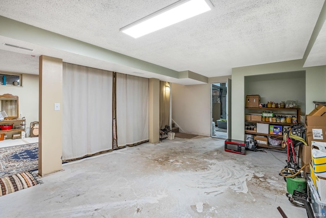 finished below grade area with visible vents, stairway, and a textured ceiling