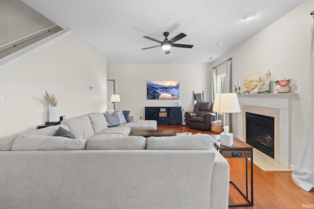 living room with a fireplace with flush hearth, wood finished floors, and a ceiling fan