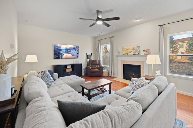 living room with a fireplace with flush hearth, wood finished floors, a wealth of natural light, and baseboards