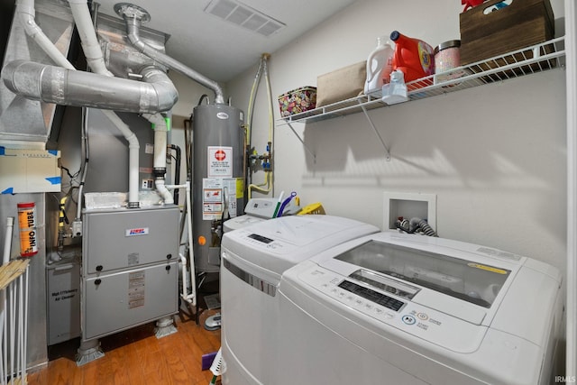 laundry area featuring gas water heater, laundry area, wood finished floors, visible vents, and washer and clothes dryer