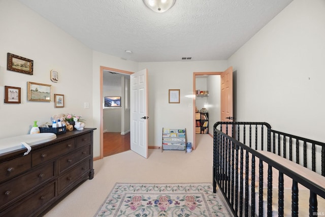 bedroom featuring a textured ceiling, visible vents, and light colored carpet