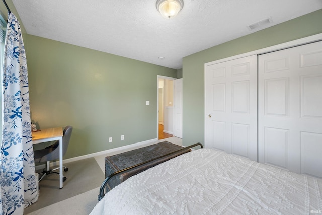 bedroom featuring baseboards, visible vents, a textured ceiling, carpet flooring, and a closet