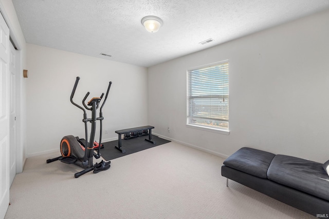 workout room featuring carpet floors, baseboards, visible vents, and a textured ceiling