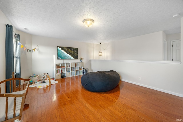 sitting room with a textured ceiling, baseboards, and wood finished floors