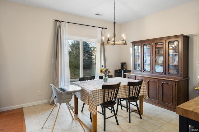 dining area with light tile patterned flooring, a notable chandelier, visible vents, and baseboards