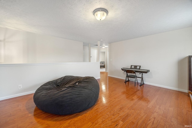 sitting room with a textured ceiling, wood finished floors, and baseboards