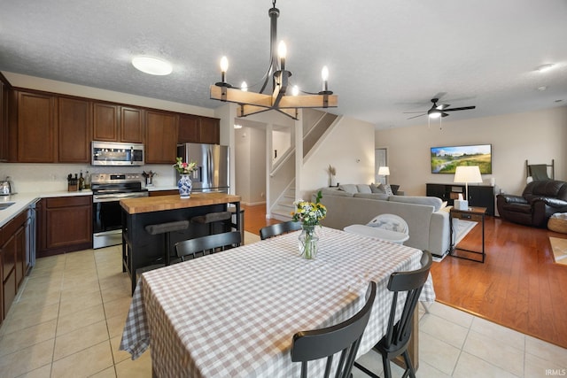 dining space with stairs, a ceiling fan, a textured ceiling, and light tile patterned floors