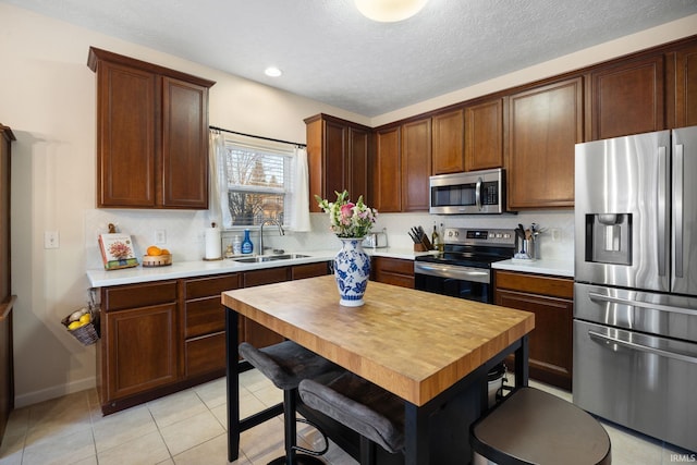 kitchen with light tile patterned floors, appliances with stainless steel finishes, light countertops, and a sink