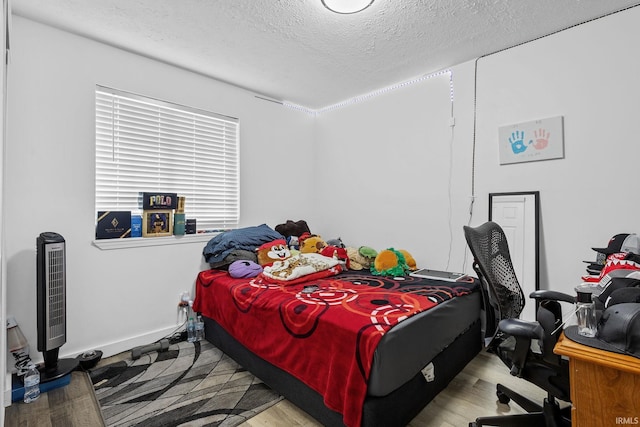 bedroom featuring a textured ceiling, wood finished floors, and baseboards