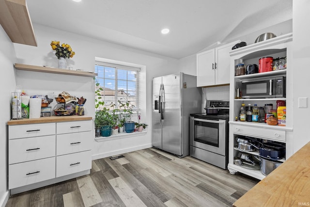 kitchen with light wood finished floors, white cabinetry, appliances with stainless steel finishes, and open shelves