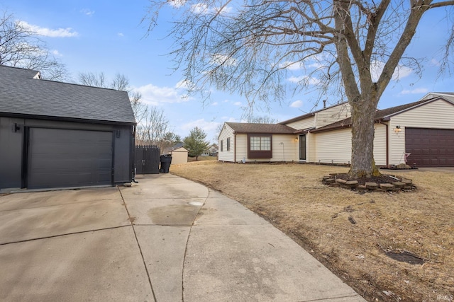 view of side of home with driveway, a shingled roof, and a garage