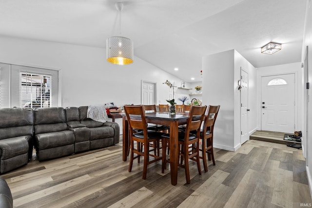 dining space with vaulted ceiling, baseboards, and wood finished floors