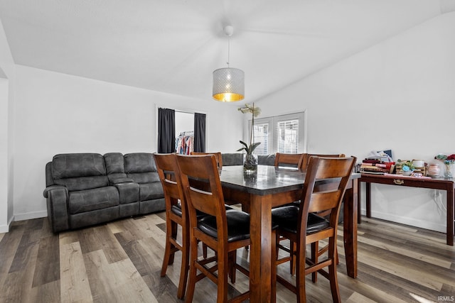 dining area featuring dark wood-style floors, lofted ceiling, and baseboards