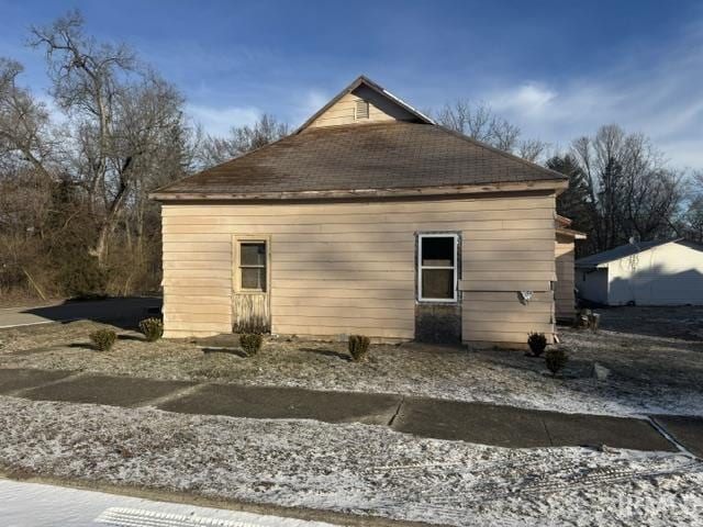 view of side of home with roof with shingles