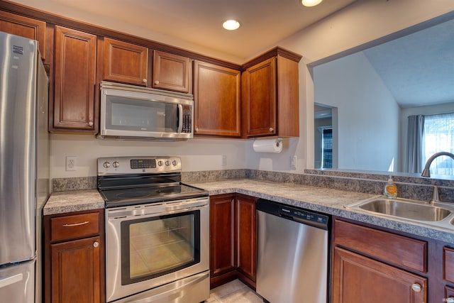 kitchen with brown cabinets, light tile patterned floors, recessed lighting, appliances with stainless steel finishes, and a sink