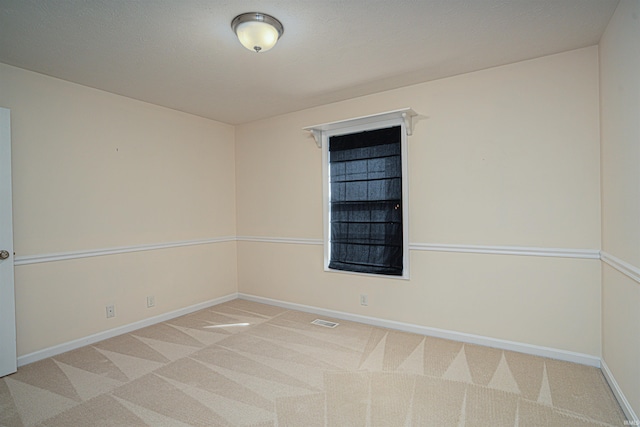 unfurnished room with carpet, visible vents, and baseboards