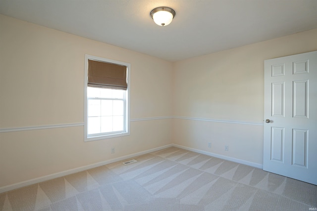 empty room featuring baseboards, visible vents, and light colored carpet