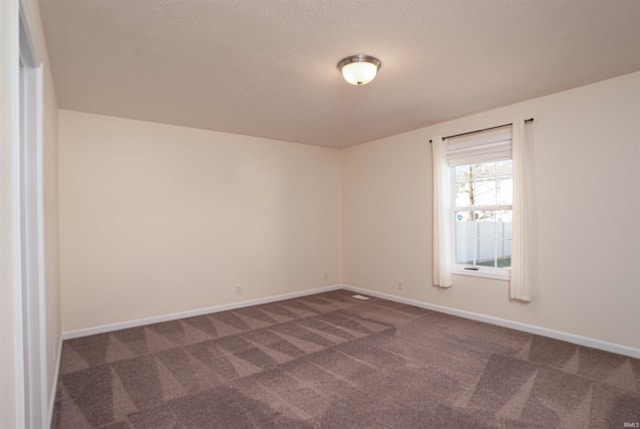 unfurnished room with dark carpet and baseboards