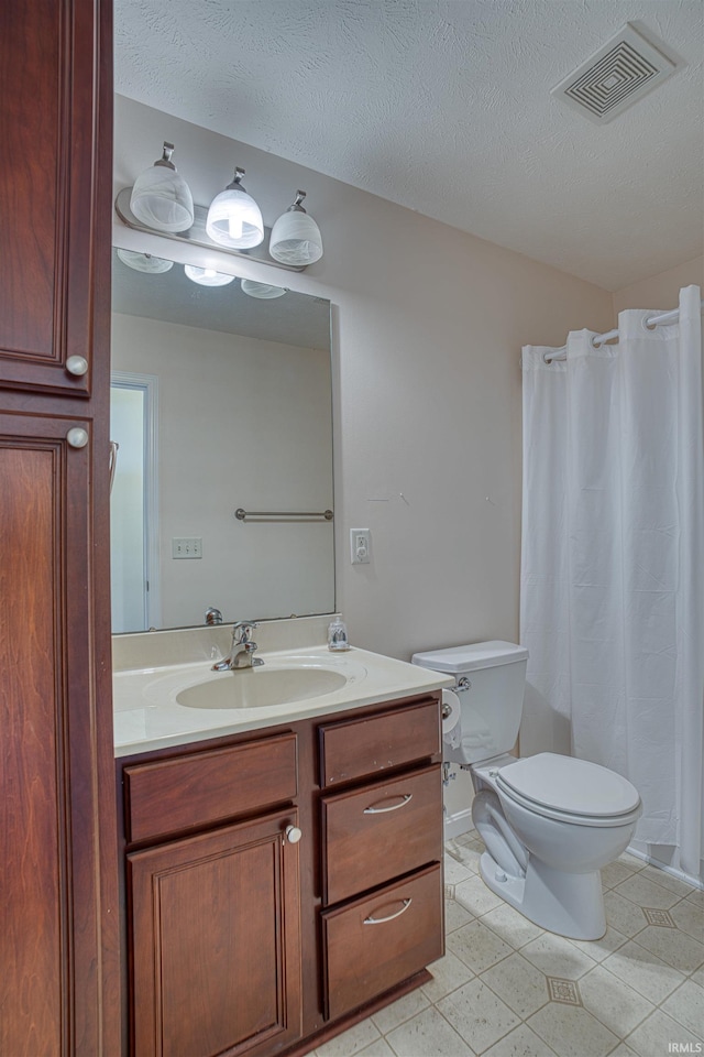 bathroom featuring visible vents, vanity, toilet, and a textured ceiling