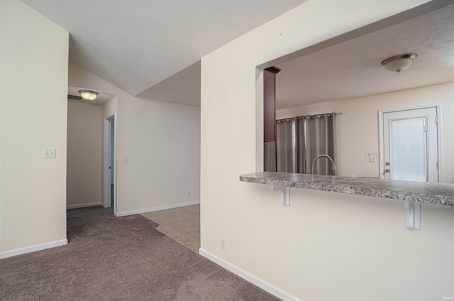 interior space with carpet flooring, vaulted ceiling, and baseboards