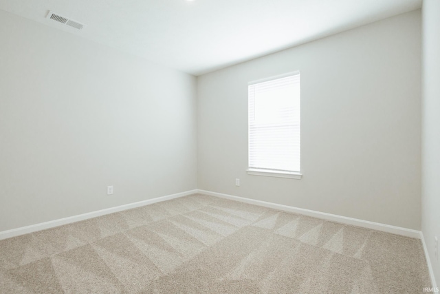 empty room featuring light colored carpet, visible vents, and baseboards