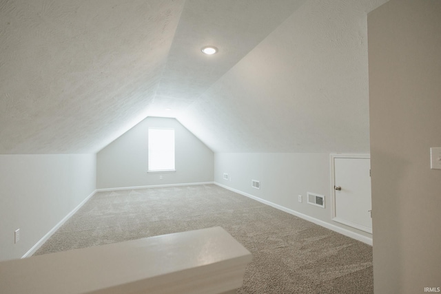 bonus room with carpet, visible vents, vaulted ceiling, a textured ceiling, and baseboards