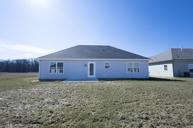 back of property with a patio area, a shingled roof, central AC, and a yard