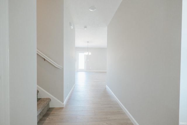 hall with stairs, light wood-type flooring, and baseboards