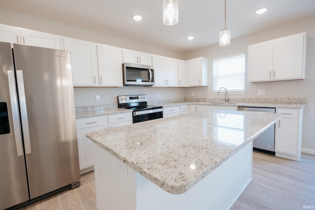 kitchen with appliances with stainless steel finishes, white cabinets, a sink, and pendant lighting