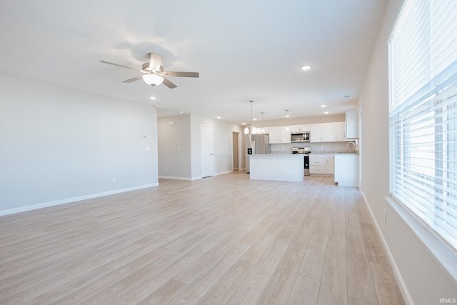 unfurnished living room with a ceiling fan, recessed lighting, light wood-style flooring, and baseboards