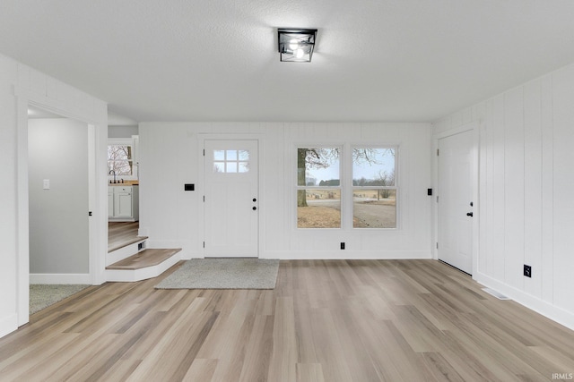 entrance foyer featuring light wood-style floors, a textured ceiling, and baseboards