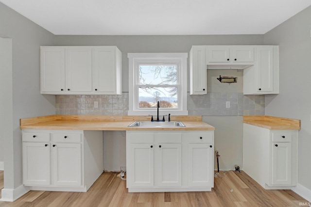 kitchen with light wood-style floors, white cabinetry, and a sink