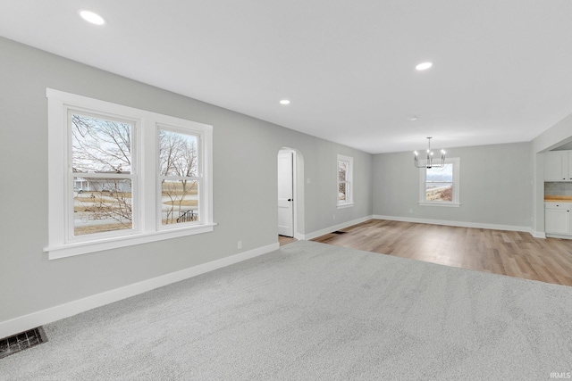 unfurnished living room with baseboards, recessed lighting, visible vents, and a notable chandelier