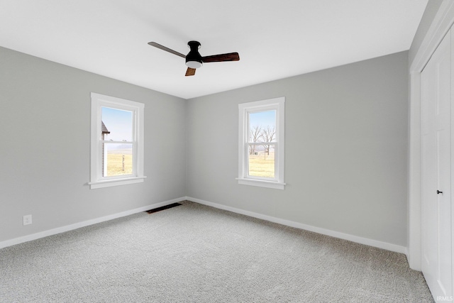 unfurnished bedroom featuring multiple windows, a closet, carpet flooring, and baseboards