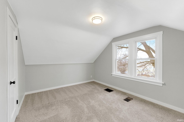 additional living space featuring lofted ceiling, carpet, baseboards, and visible vents