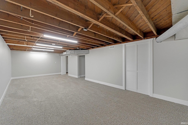 finished below grade area with light colored carpet, visible vents, and baseboards