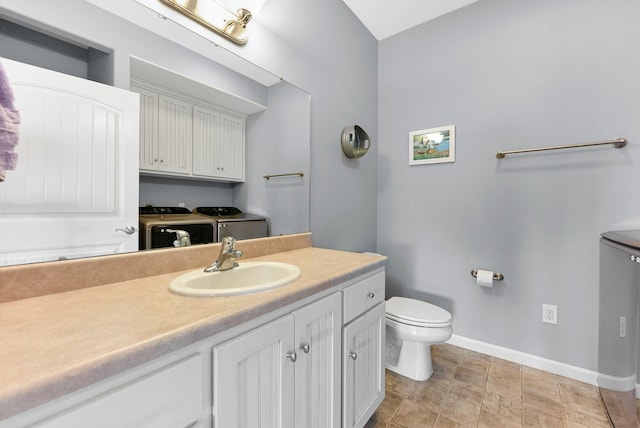 bathroom featuring baseboards, vanity, toilet, and separate washer and dryer