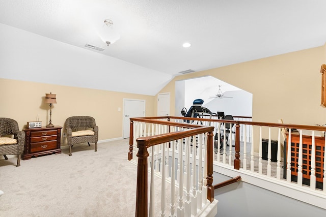 hall featuring light carpet, visible vents, vaulted ceiling, and an upstairs landing