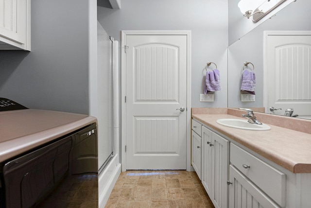 bathroom with vanity, a shower with door, and washer / dryer