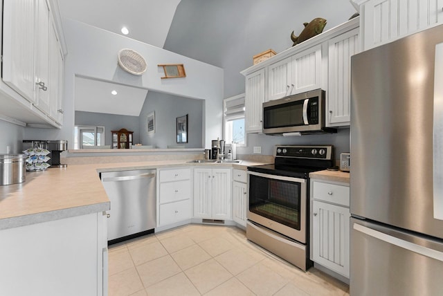 kitchen with lofted ceiling, light tile patterned flooring, stainless steel appliances, a sink, and light countertops