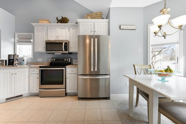 kitchen with a notable chandelier, stainless steel appliances, light countertops, light tile patterned flooring, and white cabinetry