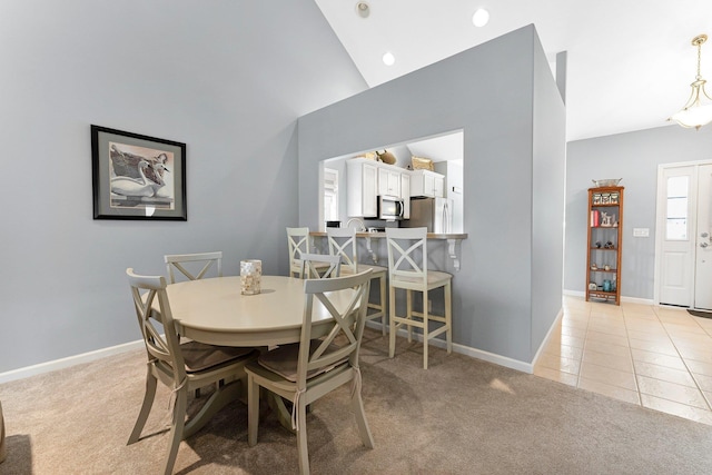 dining area featuring light tile patterned floors, baseboards, high vaulted ceiling, and light colored carpet