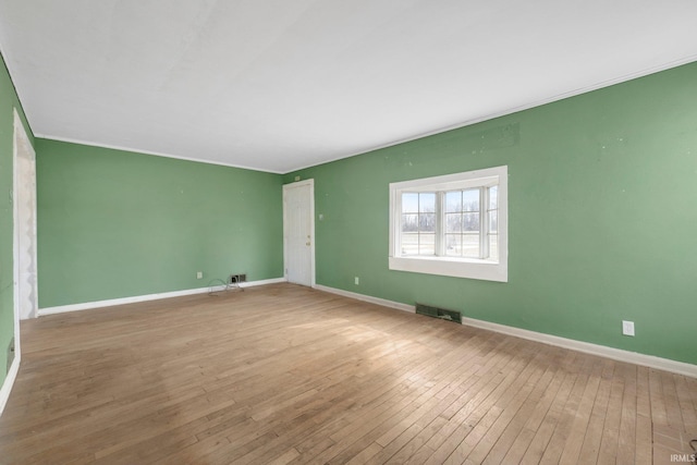 unfurnished room featuring ornamental molding, baseboards, visible vents, and hardwood / wood-style floors