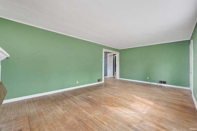 spare room featuring ornamental molding, wood-type flooring, visible vents, and baseboards