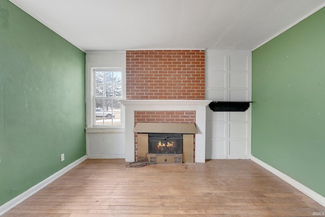 unfurnished living room featuring wood-type flooring, a fireplace, and baseboards