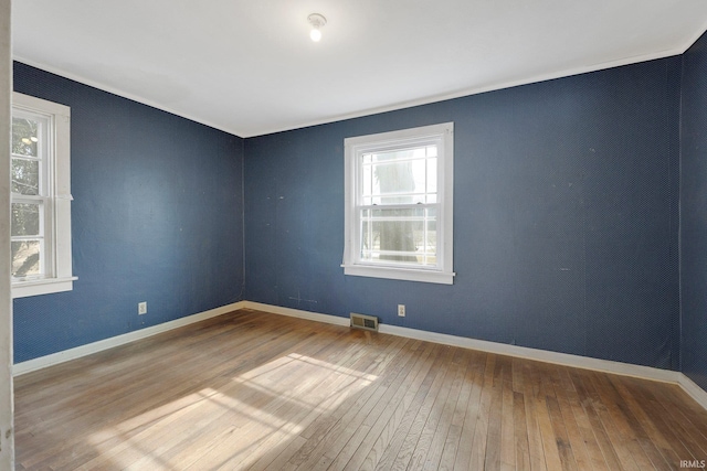 unfurnished room featuring hardwood / wood-style flooring, visible vents, and baseboards